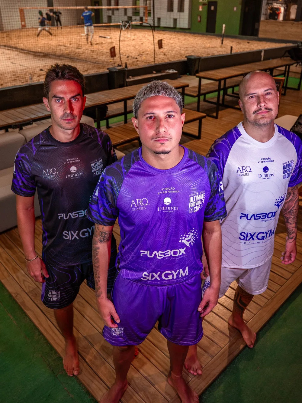Trio masculino com uniforme roxo e branco e logos de patrocinadores